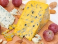 assorted cheeses, grapes and nuts on a wooden cutting board